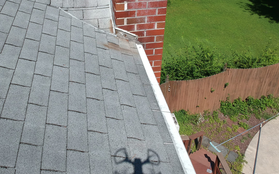 Shingle roof with shadow of a drone over it.